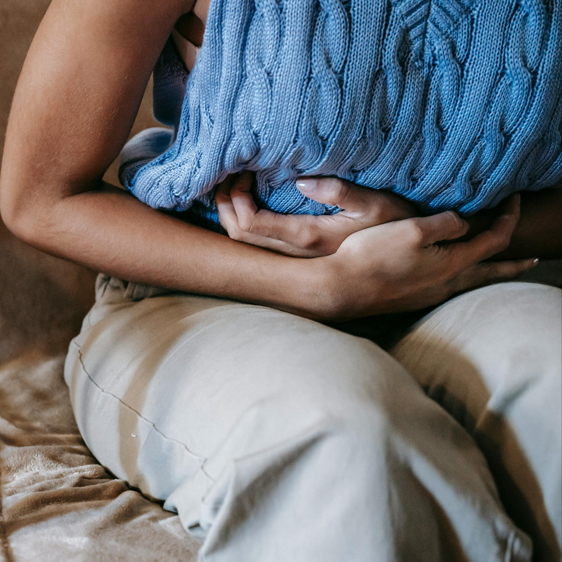 Woman experiencing period pain, representing the difference between normal cramping and signs of endometriosis or adenomyosis