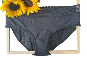 Black underwear with lace trim on a wooden frame, accompanied by sunflowers.