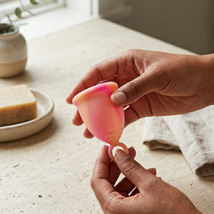 Person holding a pink silicone cup on a kitchen counter.
